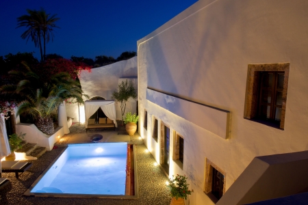Elevated night photo of courtyard and pool of Mansion sophia heritage villa in Megalochori Santorini