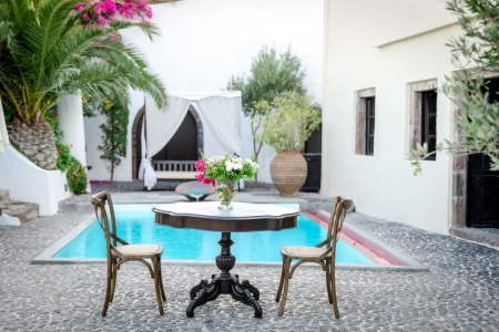 A table with flowers at the courtyard of Mansion Sophia Heritage villa in Santorini